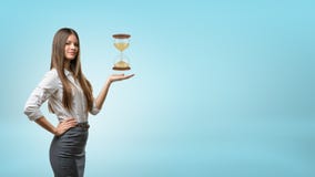 Une femme d'affaires blonde tient et tient une paume de main avec un grand sablier planant au-dessus de lui photo libre de droits Une femme d'affaires blonde tient et tient une paume de main avec un grand sablier planant au-dessus de lui photo libre de droits