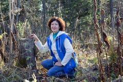 Une femme heureuse s'assied près du tronçon dans la forêt d'automne image libre de droits Une femme heureuse s'assied près du tronçon dans la forêt d'automne image libre de droits