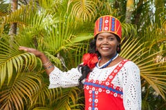 Une femme joyeuse d'Afro-am?ricain dans une robe russe nationale color?e lumineuse pose dans le jardin dans la perspective du bea photos stock Une femme joyeuse d'Afro-am?ricain dans une robe russe nationale color?e lumineuse pose dans le jardin dans la perspective du bea photos stock