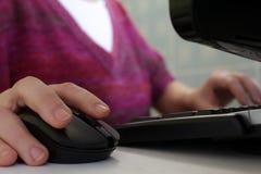 Une femme travaillant à un ordinateur Main sur la souris photographie stock libre de droits Une femme travaillant à un ordinateur Main sur la souris photographie stock libre de droits