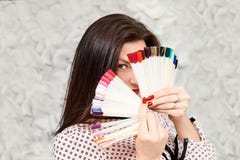 Une fille avec une belle manucure, tenant des échantillons de manucure, couvrant son visage Brunette image stock Une fille avec une belle manucure, tenant des échantillons de manucure, couvrant son visage Brunette image stock