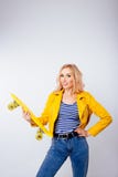 Une fille blonde mince avec un patin jaune dans des ses mains sur un fond blanc d'isolement photographie stock Une fille blonde mince avec un patin jaune dans des ses mains sur un fond blanc d'isolement photographie stock
