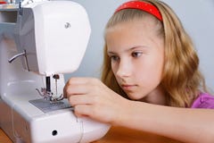 Une fille d'adolescent apprend à fileter une aiguille dans une machine à coudre moderne image libre de droits Une fille d'adolescent apprend à fileter une aiguille dans une machine à coudre moderne image libre de droits
