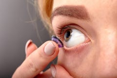 Une fille se met dans une lentille en gros plan images libres de droits Une fille se met dans une lentille en gros plan images libres de droits