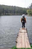 Une fille triste seul se tient sur le pilier ? c?t? du lac Fond de for?t port dans l'?quipement de protection d'?quipement de mot image stock Une fille triste seul se tient sur le pilier ? c?t? du lac Fond de for?t port dans l'?quipement de protection d'?quipement de mot image stock