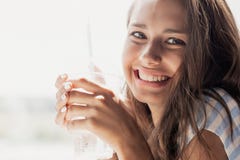 Une jeune belle fille de sourire mince avec de longs cheveux, style occasionnel de port, regarde la caméra et tient un verre, photo libre de droits Une jeune belle fille de sourire mince avec de longs cheveux, style occasionnel de port, regarde la caméra et tient un verre, photo libre de droits