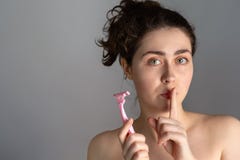 Une jeune femme tient un rasoir dans des ses mains et couvre ses lèvres dans le silence Le concept de se débarasser du massage fa images stock Une jeune femme tient un rasoir dans des ses mains et couvre ses lèvres dans le silence Le concept de se débarasser du massage fa images stock