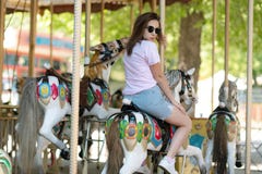 Une jeune fille avec des verres montant sur des chevaux d'un carrousel image libre de droits Une jeune fille avec des verres montant sur des chevaux d'un carrousel image libre de droits