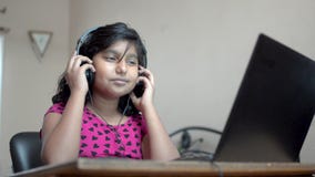 Une joyeuse jeune fille asiatique vêtue d'un casque et écoutant de la musique sur un ordinateur portable, dansant et chantant clips vidéos Une joyeuse jeune fille asiatique vêtue d'un casque et écoutant de la musique sur un ordinateur portable, dansant et chantant clips vidéos