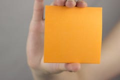 Une main femelle tient un blanc propre orange d'autocollant photographie stock Une main femelle tient un blanc propre orange d'autocollant photographie stock