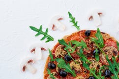 Une moitié de pizza végétarienne faite maison avec le rucola frais, tomates, olives noires sur la fin blanche de table Images libres de droits Une moitié de pizza végétarienne faite maison avec le rucola frais, tomates, olives noires sur la fin blanche de table Images libres de droits