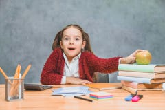 Une petite fille mignonne espi?gle a l'amusement tout en comptant sur les livres ?pais sur un fond gris Ses cheveux sont faits de images stock Une petite fille mignonne espi?gle a l'amusement tout en comptant sur les livres ?pais sur un fond gris Ses cheveux sont faits de images stock