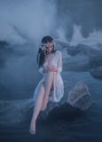 Une sirène seule, se reposant sur une roche au milieu de la rivière, qui a été serrée par un brouillard épais et impénétrable sur Image libre de droits Une sirène seule, se reposant sur une roche au milieu de la rivière, qui a été serrée par un brouillard épais et impénétrable sur Image libre de droits