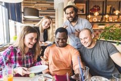 Une soci?t? des jeunes multiculturels dans un caf? mangeant de la pizza, cocktails potables, ayant l'amusement photo libre de droits Une soci?t? des jeunes multiculturels dans un caf? mangeant de la pizza, cocktails potables, ayant l'amusement photo libre de droits