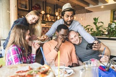Une soci?t? des jeunes multiculturels dans un caf? mangeant de la pizza, cocktails potables, ayant l'amusement image stock Une soci?t? des jeunes multiculturels dans un caf? mangeant de la pizza, cocktails potables, ayant l'amusement image stock