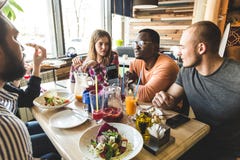 Une soci?t? des jeunes multiculturels dans un caf? mangeant de la pizza, cocktails potables, ayant l'amusement photographie stock libre de droits Une soci?t? des jeunes multiculturels dans un caf? mangeant de la pizza, cocktails potables, ayant l'amusement photographie stock libre de droits