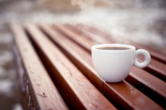 Une tasse blanche de supports de café sur les conseils en bois dans l'environnement naturel pendant l'hiver photographie stock libre de droits Une tasse blanche de supports de café sur les conseils en bois dans l'environnement naturel pendant l'hiver photographie stock libre de droits