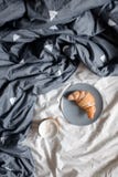 Une tasse de café et d'un croissant d'un plat sur un lit confortable Photo libre de droits Une tasse de café et d'un croissant d'un plat sur un lit confortable Photo libre de droits