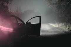 Une voiture avec elle est allumée les phares et la porte ouverte sur les WI brumeux fantasmagoriques photo libre de droits Une voiture avec elle est allumée les phares et la porte ouverte sur les WI brumeux fantasmagoriques photo libre de droits
