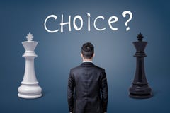 Une vue sur un dos du ` s d'homme d'affaires comme il se tient entre deux rois d'échecs et un choix de lettrage Photographie stock libre de droits Une vue sur un dos du ` s d'homme d'affaires comme il se tient entre deux rois d'échecs et un choix de lettrage Photographie stock libre de droits