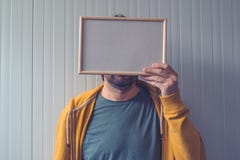 Unerkennbarer Mann, der mit leerem Bilderrahmen über seinem Gesicht aufwirft Stockbilder Unerkennbarer Mann, der mit leerem Bilderrahmen über seinem Gesicht aufwirft Stockbilder