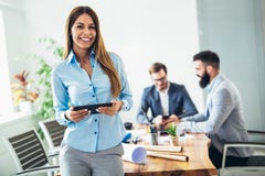 Ung affärskvinna som använder den digitala minnestavlan medan kollega i bakgrund royaltyfria bilder Ung affärskvinna som använder den digitala minnestavlan medan kollega i bakgrund royaltyfria bilder