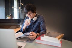 Ung asiatisk manuniversitetsstudentläsebok i arkiv royaltyfri bild Ung asiatisk manuniversitetsstudentläsebok i arkiv royaltyfri bild