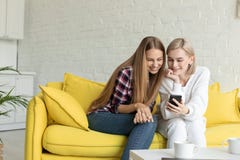 Ung attraktiv kvinna tv? i tillf?llig kl?der som hemma sitter p? den gula soffan arkivbilder Ung attraktiv kvinna tv? i tillf?llig kl?der som hemma sitter p? den gula soffan arkivbilder