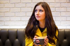Ung brunettkvinna i en kaffehöftcoffee shop som dricker en cappuccino royaltyfri foto Ung brunettkvinna i en kaffehöftcoffee shop som dricker en cappuccino royaltyfri foto