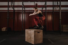Ung crossfitkvinna som gör asken som hoppar på idrottshallen royaltyfri foto Ung crossfitkvinna som gör asken som hoppar på idrottshallen royaltyfri foto