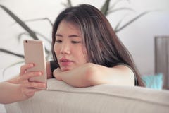Ung för vardagsrumsoffa för härlig och avkopplad asiatisk kinesisk kvinna liggande hemmastadd soffa genom att använda internet på arkivfoton Ung för vardagsrumsoffa för härlig och avkopplad asiatisk kinesisk kvinna liggande hemmastadd soffa genom att använda internet på arkivfoton
