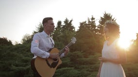 Ung hipstergrupp av vänner som tycker om som spelar tillsammans gitarren och sjunger på solnedgång lager videofilmer Ung hipstergrupp av vänner som tycker om som spelar tillsammans gitarren och sjunger på solnedgång lager videofilmer