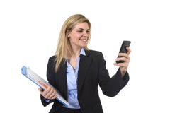 Ung härlig affärskvinna för blont hår som använder internet app på för för kontorsmapp och penna för mobiltelefon som hållande le arkivbild Ung härlig affärskvinna för blont hår som använder internet app på för för kontorsmapp och penna för mobiltelefon som hållande le arkivbild