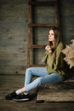 Ung härlig brunettflicka i stuckit ett varmt jeans och gymnastikskor som poserar i studio med dagsljus fotografering för bildbyråer Ung härlig brunettflicka i stuckit ett varmt jeans och gymnastikskor som poserar i studio med dagsljus fotografering för bildbyråer