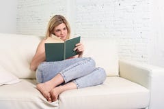 Ung härlig caucasian kvinnaläsebok som studerar att ligga som är bekvämt på den hem- soffan som ser lycklig royaltyfri fotografi Ung härlig caucasian kvinnaläsebok som studerar att ligga som är bekvämt på den hem- soffan som ser lycklig royaltyfri fotografi