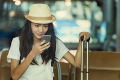 Ung kvinna i väntande på flygresa för flygplats genom att använda den smarta telefonen fotografering för bildbyråer Ung kvinna i väntande på flygresa för flygplats genom att använda den smarta telefonen fotografering för bildbyråer