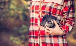 Ung kvinna med den retro fotokameran och utomhus- plädskjorta royaltyfri bild Ung kvinna med den retro fotokameran och utomhus- plädskjorta royaltyfri bild