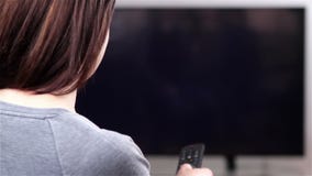 Ung kvinna med fjärrkontroll som håller ögonen på smart TV arkivfilmer Ung kvinna med fjärrkontroll som håller ögonen på smart TV arkivfilmer