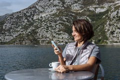 Ung kvinna som dricker kaffe och använder smarphone i morgonen a fotografering för bildbyråer Ung kvinna som dricker kaffe och använder smarphone i morgonen a fotografering för bildbyråer