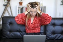 Ung kvinna som har problem med bärbara datorn, medan sitta på en lädersoffa fotografering för bildbyråer Ung kvinna som har problem med bärbara datorn, medan sitta på en lädersoffa fotografering för bildbyråer