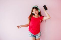 Ung kvinna som tycker om med musik från den smarta telefonen i huset, Liste arkivbild Ung kvinna som tycker om med musik från den smarta telefonen i huset, Liste arkivbild
