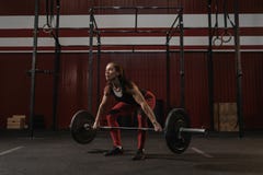 Ung kvinnlig idrottsman nen som gör deadliftövning Stark kvinna som lyfter den tunga skivstången på crossfitidrottshallen royaltyfri bild Ung kvinnlig idrottsman nen som gör deadliftövning Stark kvinna som lyfter den tunga skivstången på crossfitidrottshallen royaltyfri bild