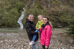 Ung lycklig familj: mamma, farsa och dotter p? bakgrunden av en bergvattenfall royaltyfri bild Ung lycklig familj: mamma, farsa och dotter p? bakgrunden av en bergvattenfall royaltyfri bild