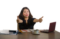 Ung lycklig och härlig asiatisk kinesisk affärskvinna som firar den upphetsade geende tummen för lyckad jobbprestation upp att ar arkivfoton Ung lycklig och härlig asiatisk kinesisk affärskvinna som firar den upphetsade geende tummen för lyckad jobbprestation upp att ar arkivfoton