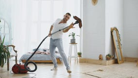 Ung man som har det roliga lokalvårdhuset med dammsugaredans arkivfoto Ung man som har det roliga lokalvårdhuset med dammsugaredans arkivfoto