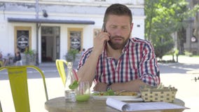 Ung man som talar vid smartphonen, under lunch-, glidare- och pannaskott lager videofilmer Ung man som talar vid smartphonen, under lunch-, glidare- och pannaskott lager videofilmer