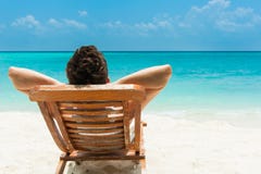 Ung man som vilar på stranden royaltyfri bild Ung man som vilar på stranden royaltyfri bild
