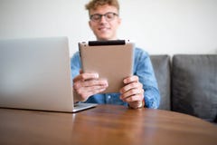 Ung manlig lyckad affärsman som arbetar med bärbar datordatoren och handlagblocket som i regeringsställning sitter royaltyfri bild Ung manlig lyckad affärsman som arbetar med bärbar datordatoren och handlagblocket som i regeringsställning sitter royaltyfri bild