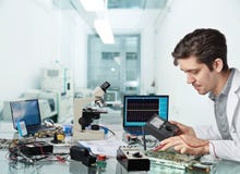 Ung manlig tech eller teknikern reparerar elektronisk utrustning arkivfoto Ung manlig tech eller teknikern reparerar elektronisk utrustning arkivfoto