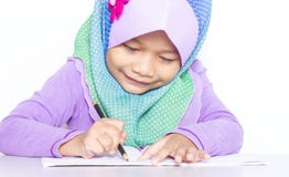 Ung muslimflicka som skriver en bok på skrivbordet royaltyfri foto Ung muslimflicka som skriver en bok på skrivbordet royaltyfri foto